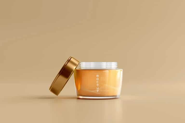 Amber glass jar with a gold lid on a beige background