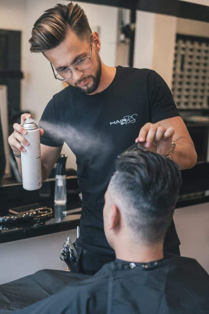 Barber spraying styling product onto a client's hair