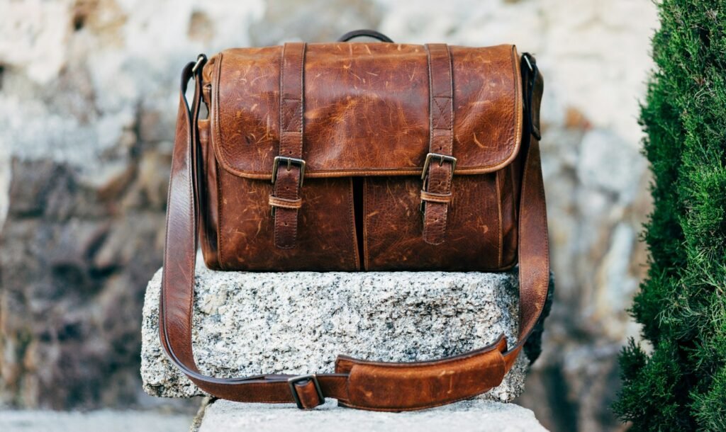 Brown leather messenger bag on a concrete ledge