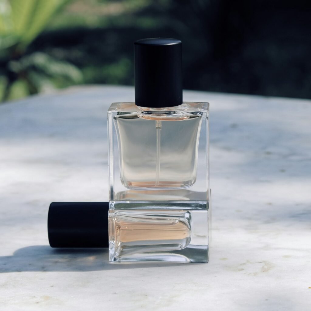 Clear glass fragrance bottle and cap on a stone surface
