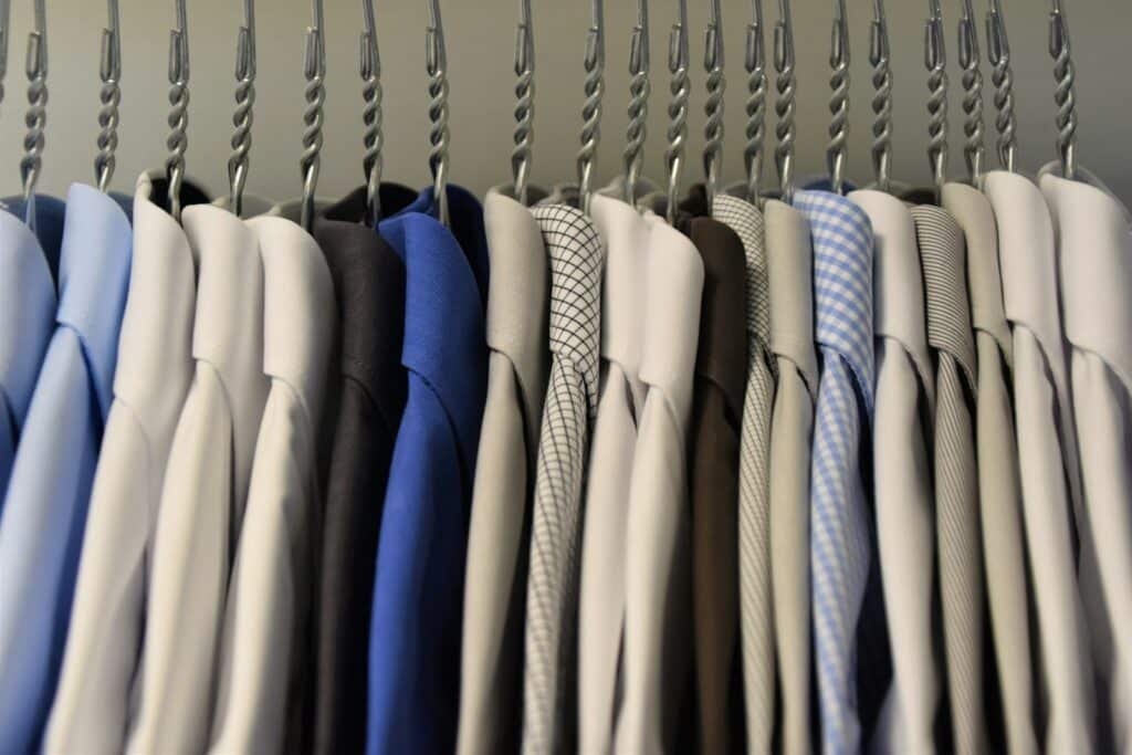 Dress shirts and suit jackets in assorted colors hanging on a rack