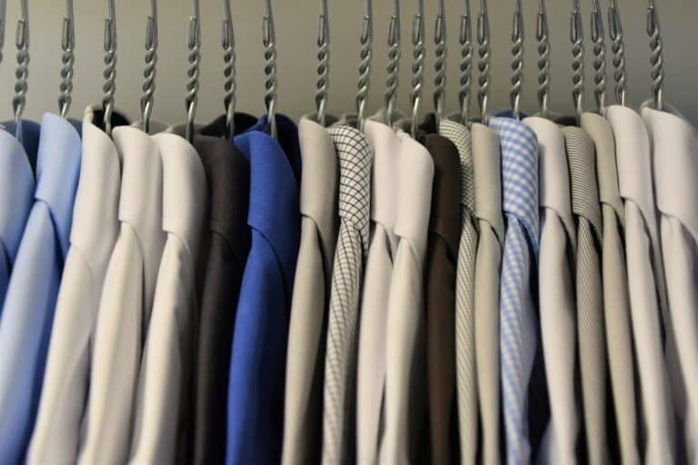 Dress shirts and suit jackets in assorted colors hanging on a rack