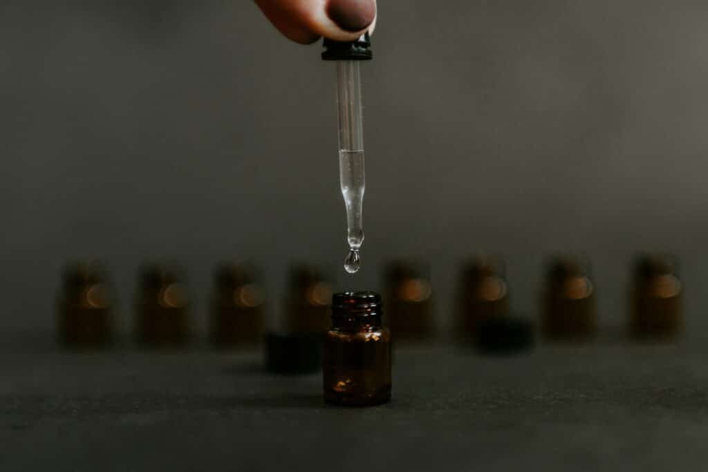 Dropper above a small amber bottle with more bottles behind