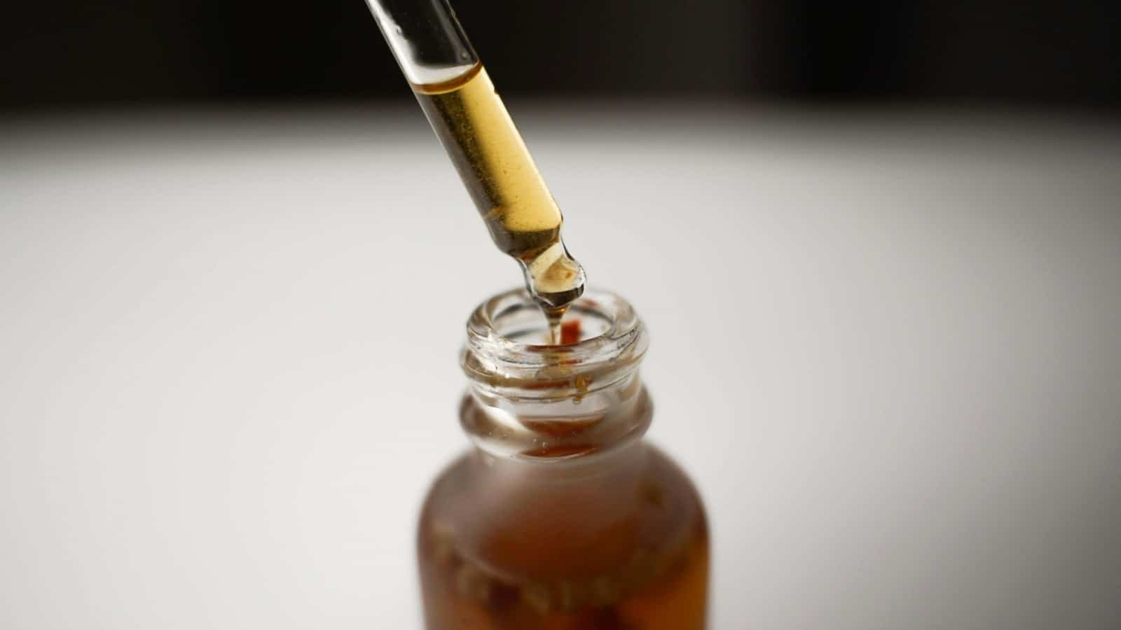 Dropper drawing serum from an amber bottle