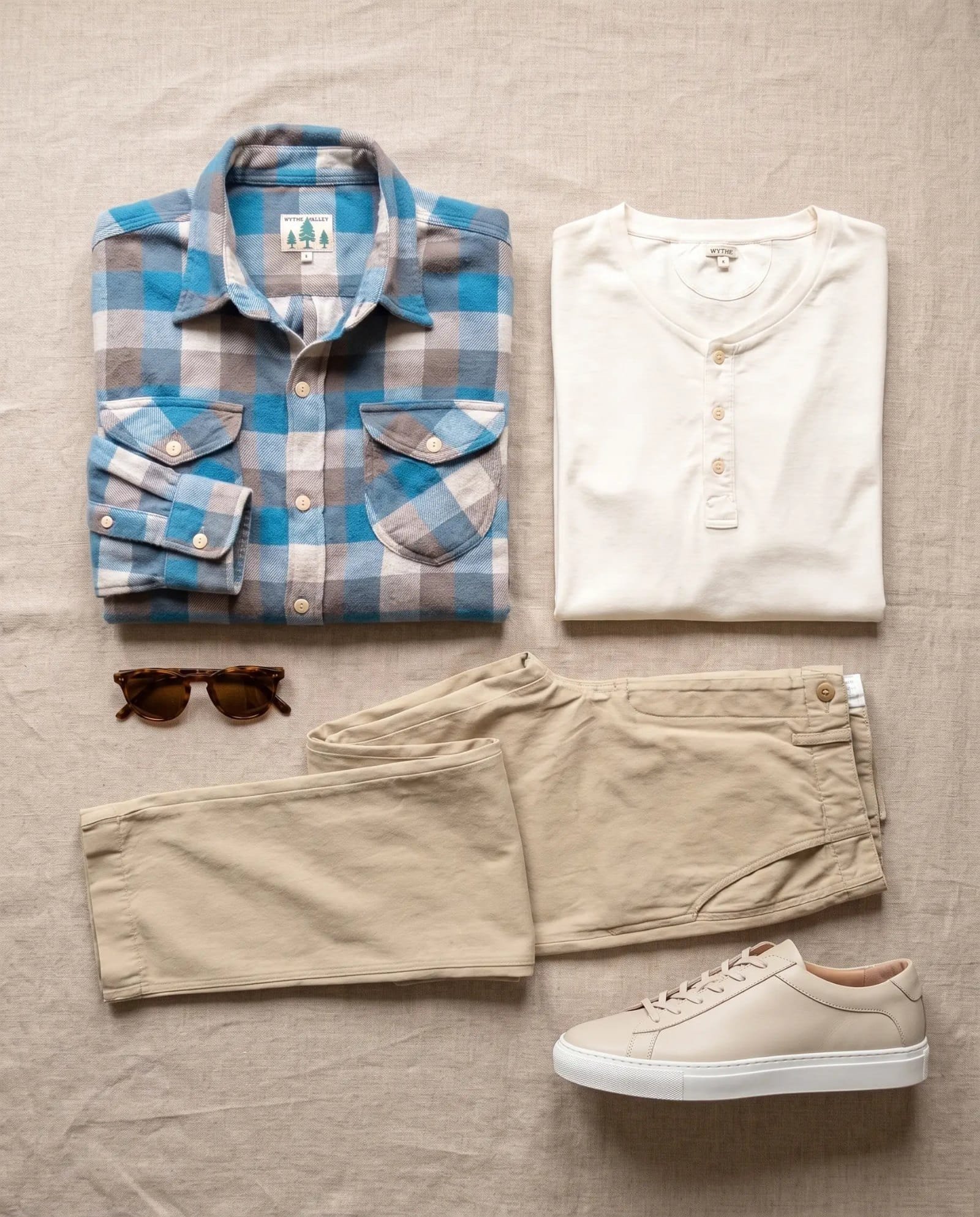 Flat lay of the Wythe washed flannel workshirt in Glacier Plaid, Wythe cotton henley in Natural, Wythe flat front cotton linen twill chino in Camp Khaki