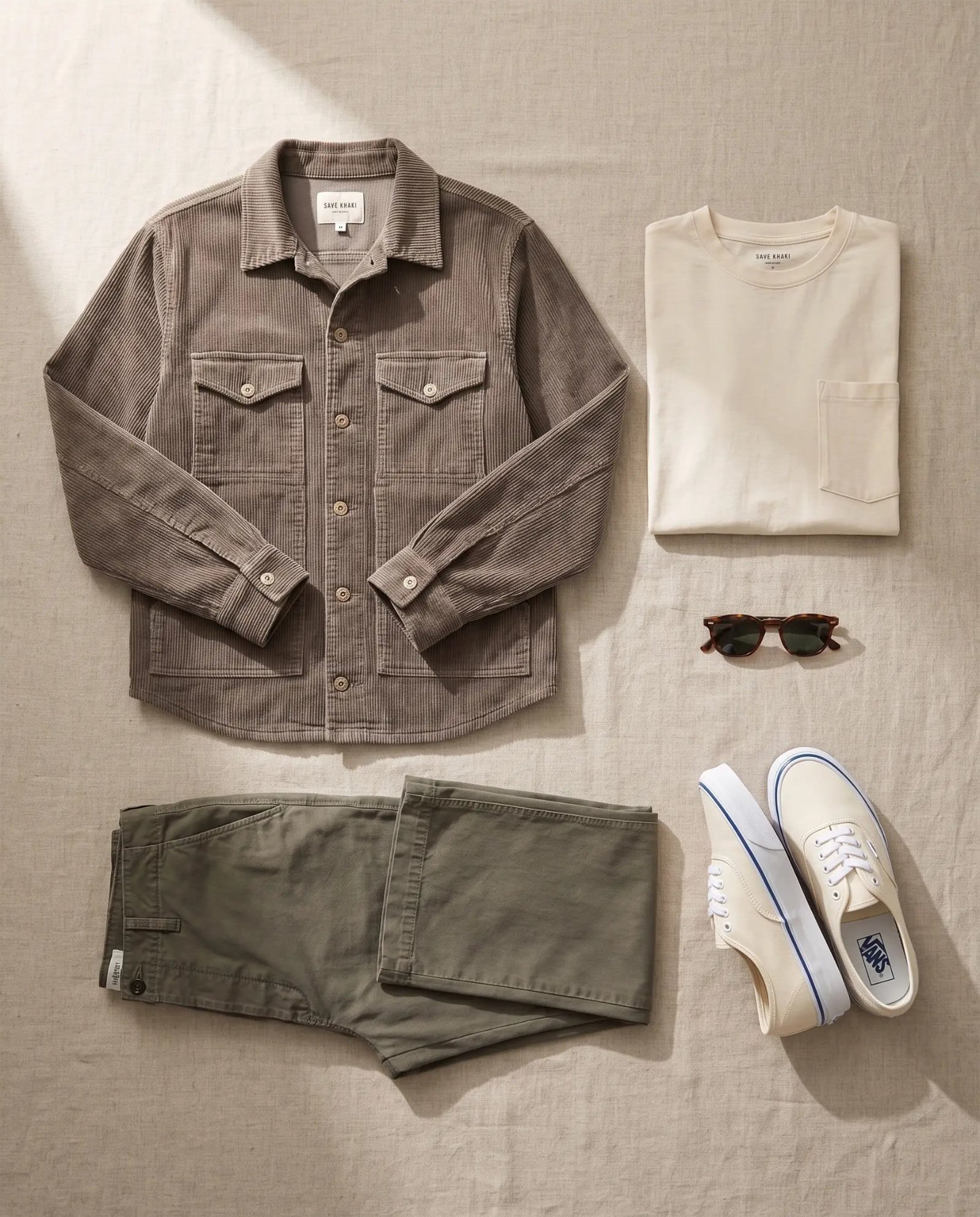 Flat lay of the Save Khaki trucker jacket, natural pocket tee, olive Weekend chino and off-white Vans