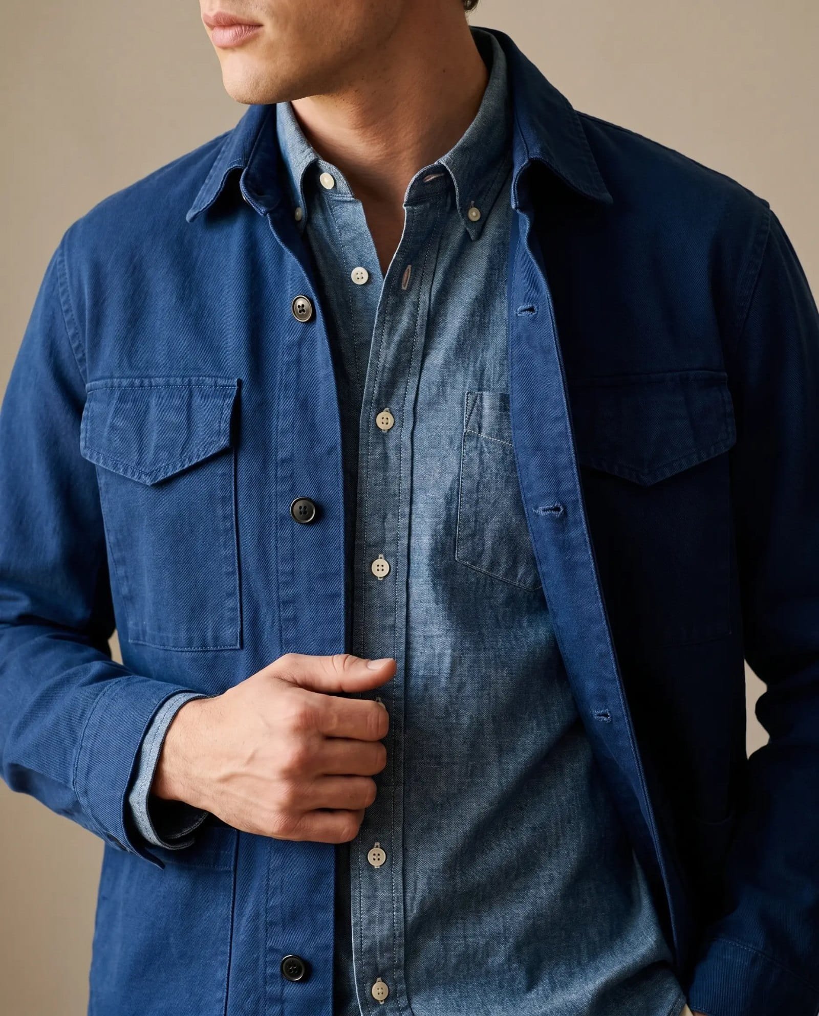 Close-up of the Alex Mill navy canvas chore jacket over a chambray shirt showing the flap pockets