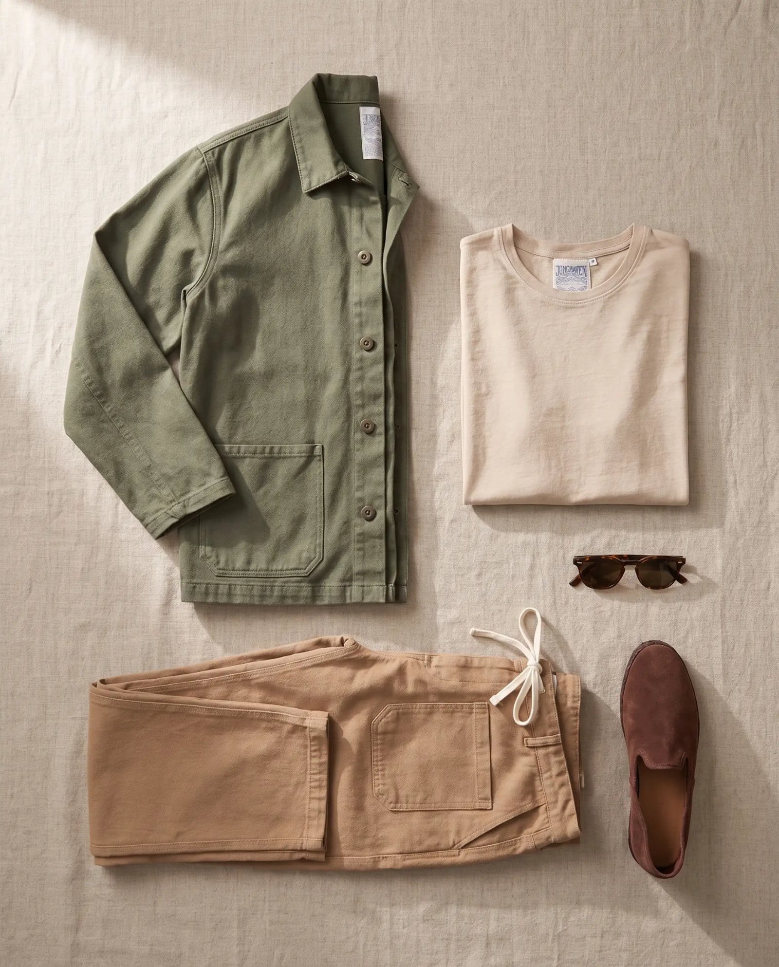 Flat lay of the Jungmaven Olympic jacket, Baja tee, Pacific Coast pant and Sabah slip-ons
