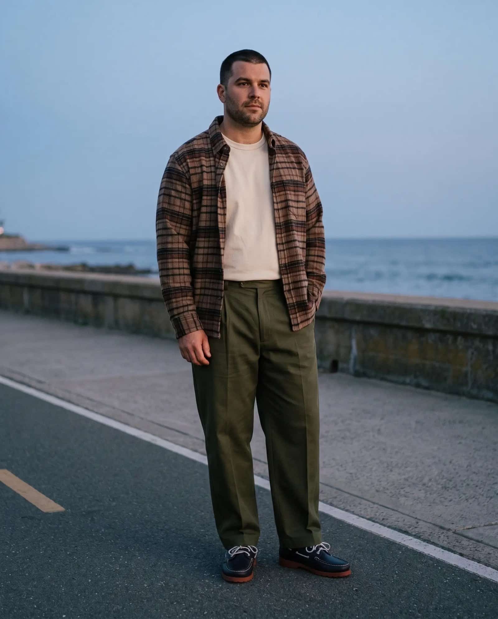 Man in the Portuguese Flannel Stalia overshirt over a Merz b. Schwanen tee with dark olive Casatlantic trousers at dusk