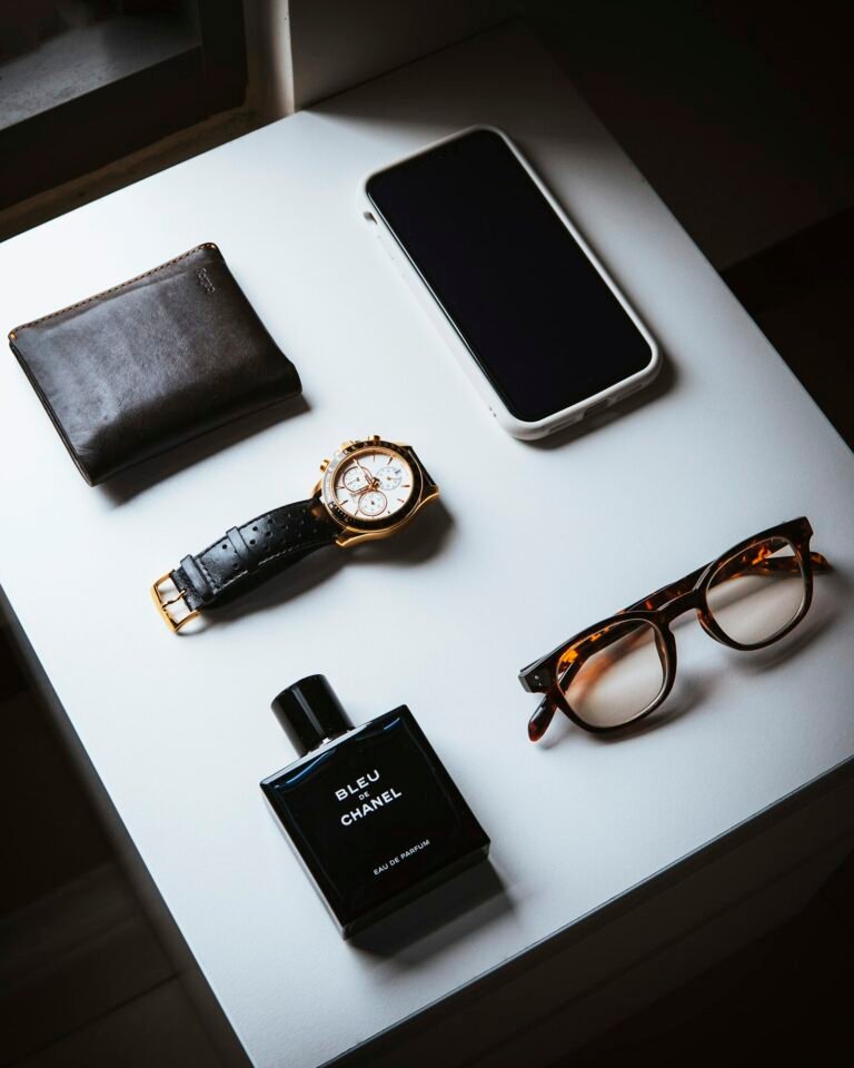 Flat lay of a wallet, watch, glasses, phone and a cologne bottle