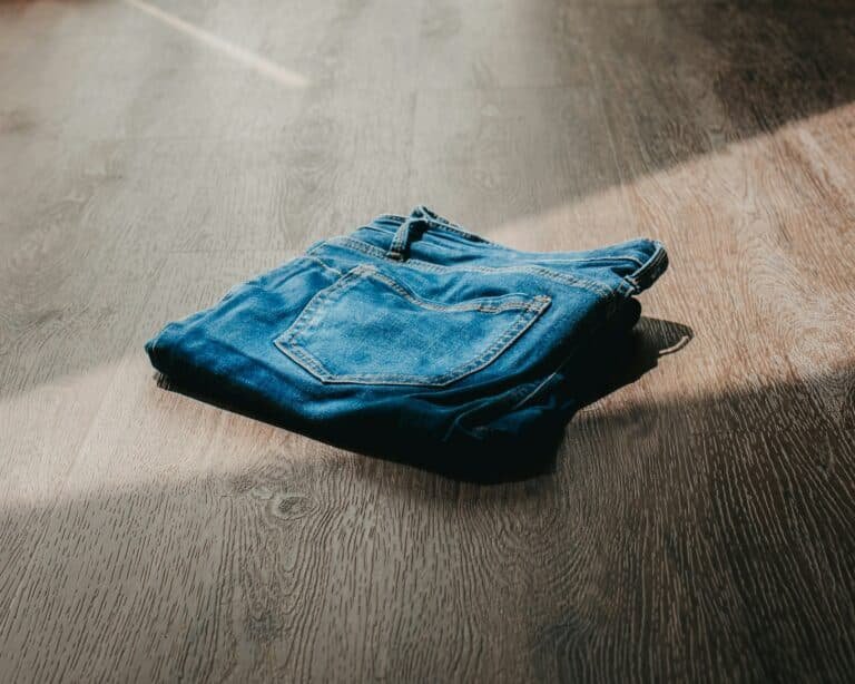 Folded blue jeans on a wooden floor