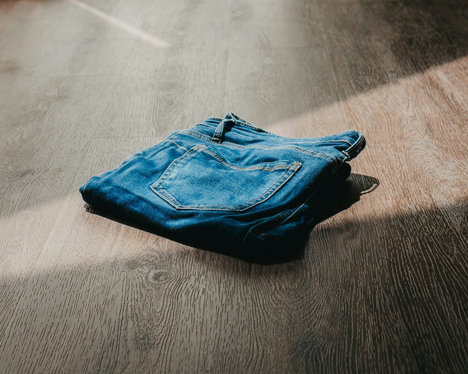 Folded blue jeans on a wooden floor