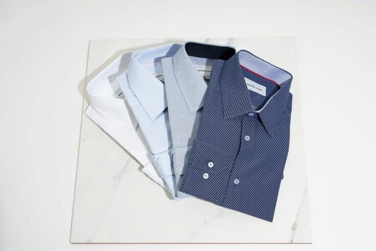 Folded dress shirts in white, light blue and navy print on a marble board