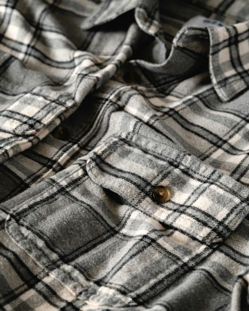 Close-up of a grey and white plaid flannel shirt with a buttoned chest pocket