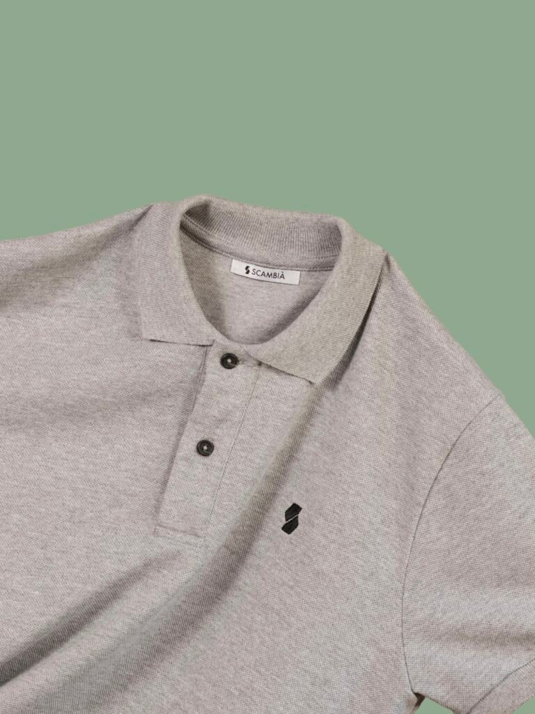 Grey polo shirt laid flat on a green background