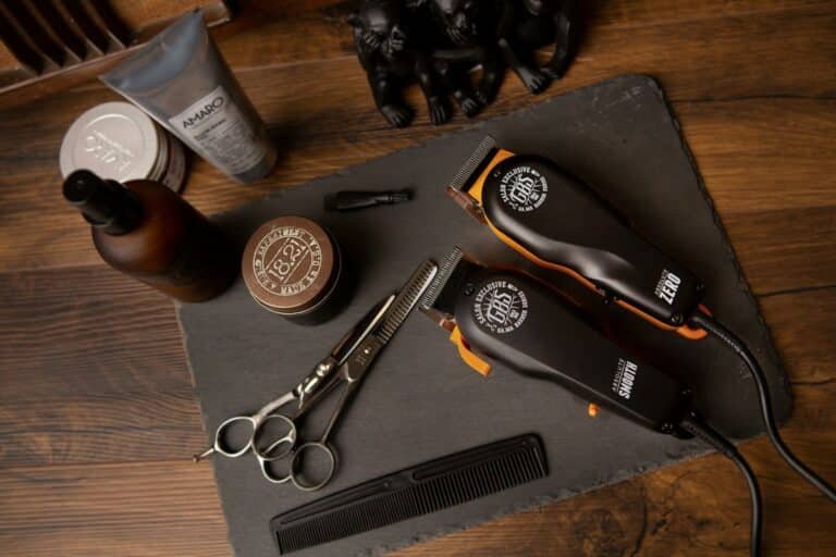 Hair clippers, scissors, a comb and grooming products on a slate board