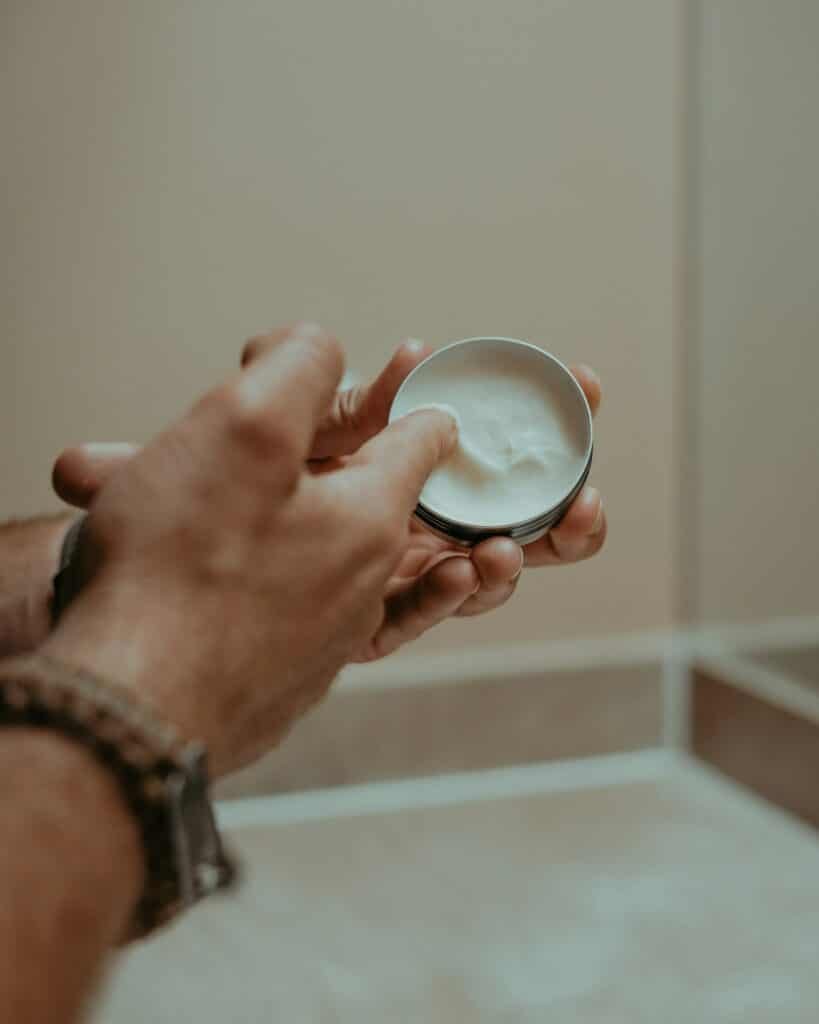 Hand holding an open tin of balm