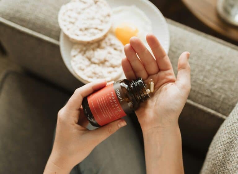 Hands pouring capsules from a supplement bottle