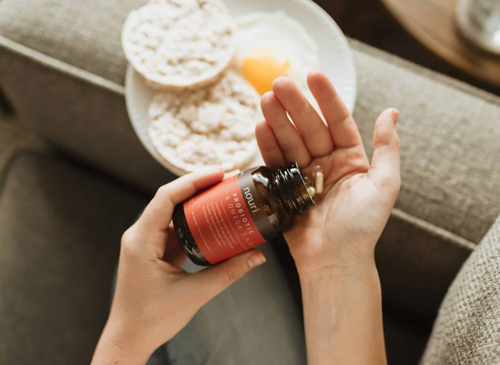 Hands pouring capsules from a supplement bottle