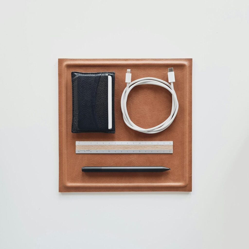 Leather valet tray holding a wallet, a charging cable and two pens