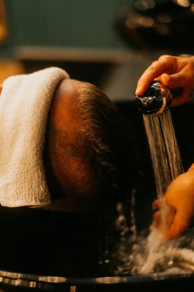 Man getting his hair rinsed at a barbershop sink
