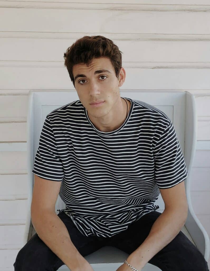 Man in a black and white striped t-shirt sitting on a white chair