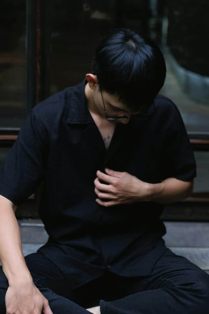 Man in a black short-sleeve shirt sitting on the ground