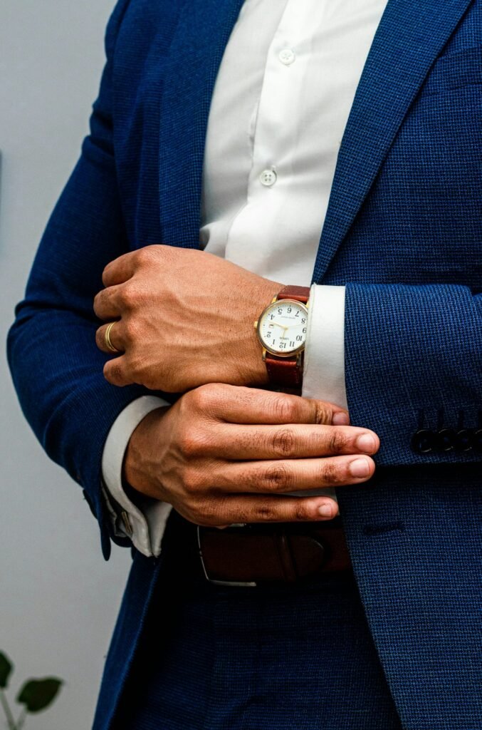Man in a blue blazer adjusting a gold wristwatch
