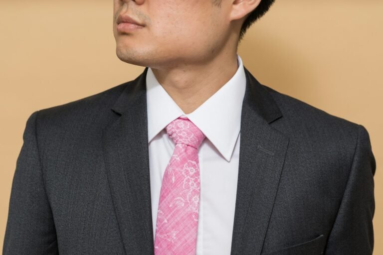Man in a charcoal suit, white dress shirt and pink tie