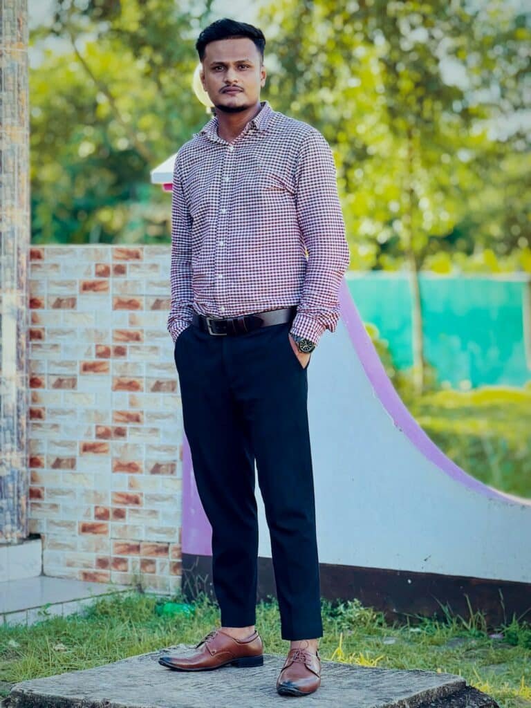 Man in a checked shirt and navy trousers standing outdoors
