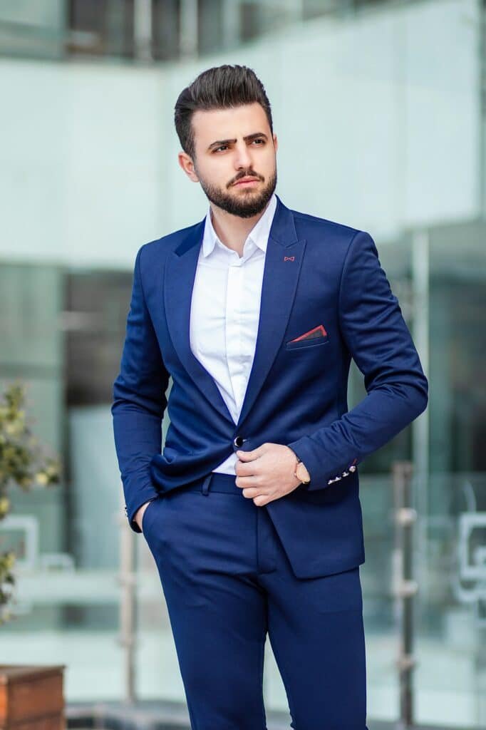 Man in a fitted blue suit and white shirt in front of a glass building