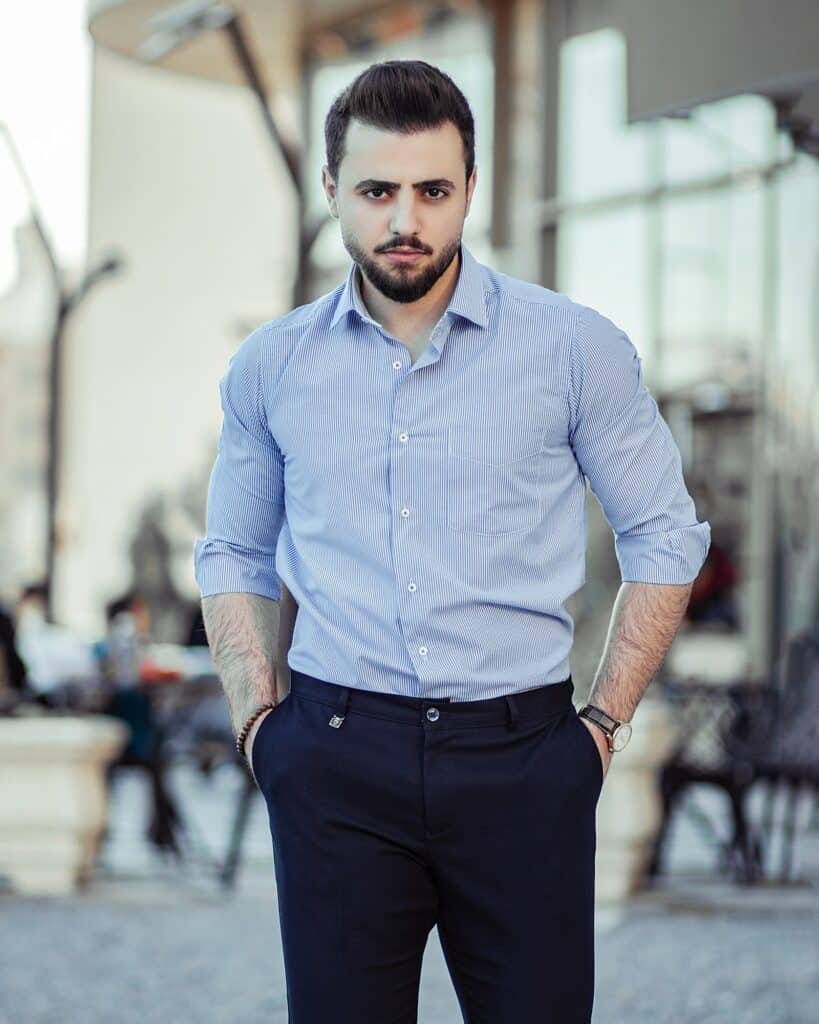 Man in a light blue button-down shirt and navy dress trousers