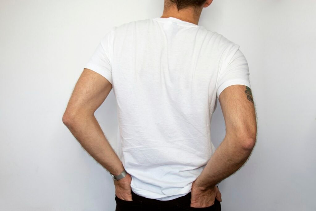 Man in a plain white t-shirt seen from behind with his hands on his back pockets