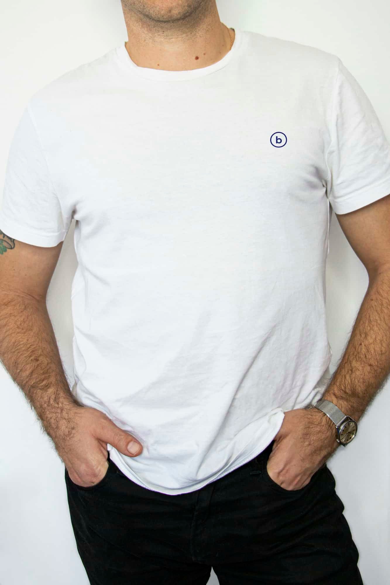 Man in a white crew neck t-shirt and dark jeans with his hands in his pockets