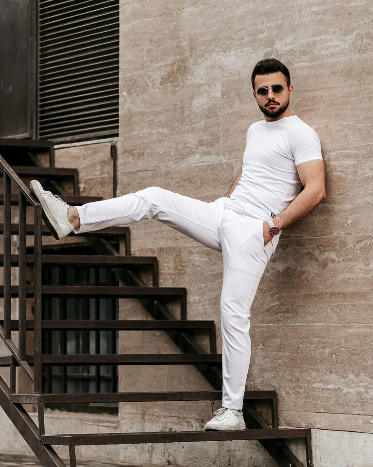 Man in a white t-shirt and white trousers on black wooden stairs