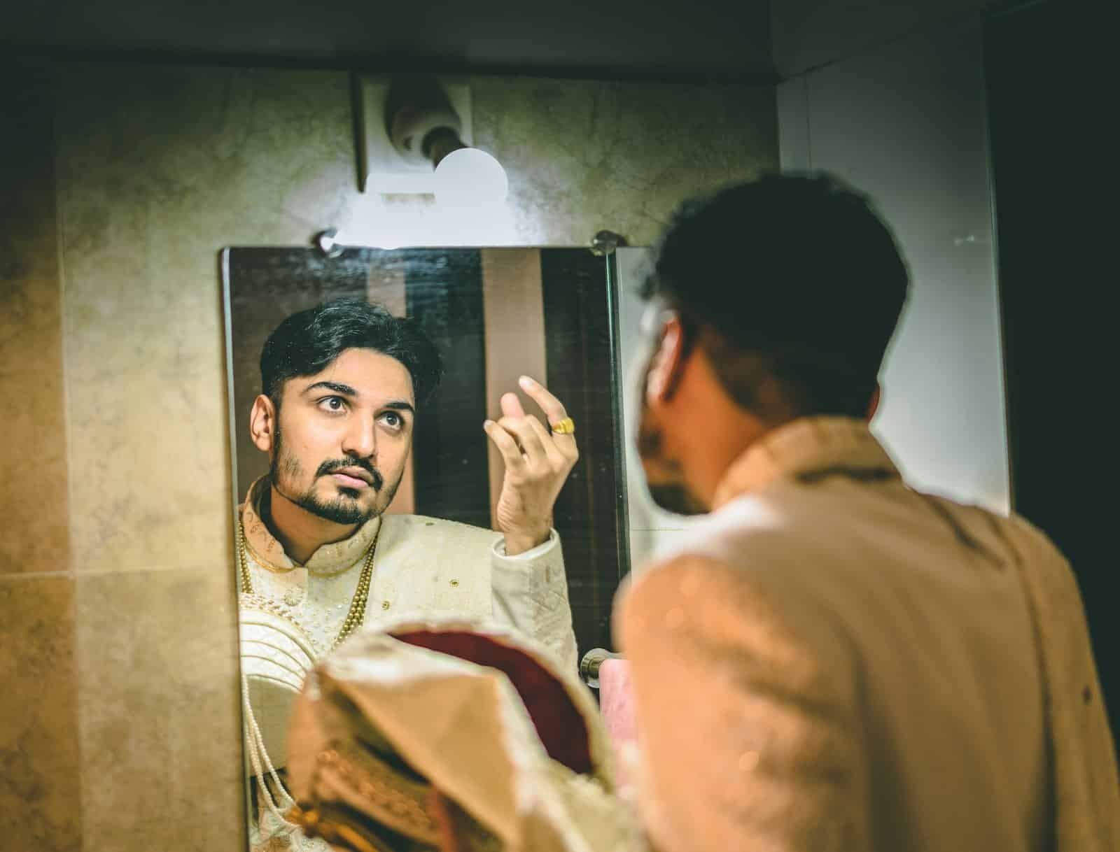 Man looking at his reflection in a bathroom mirror