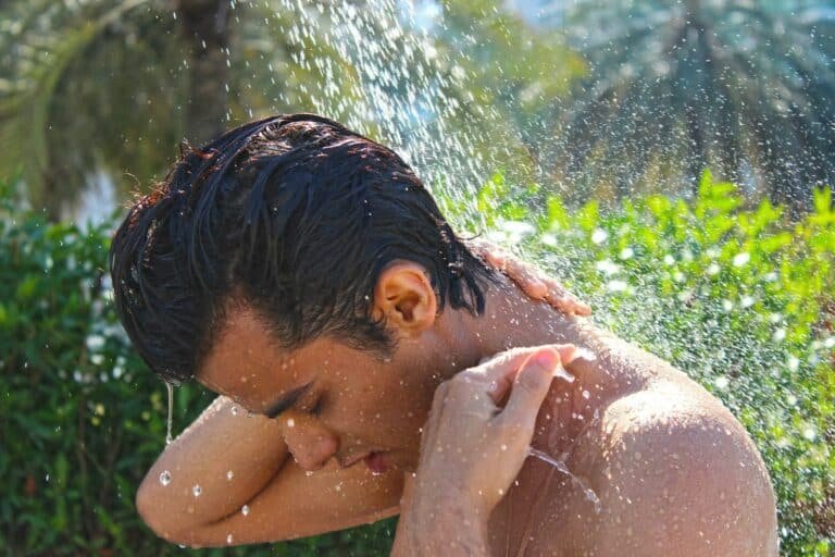 Man rinsing his hair under an outdoor shower