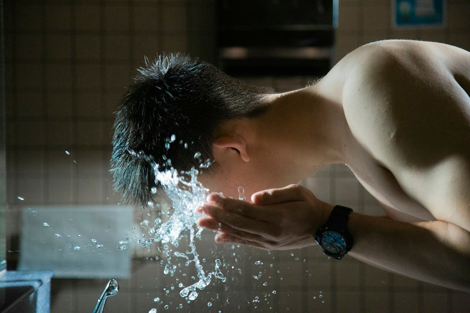 Man splashing water on his face at a sink
