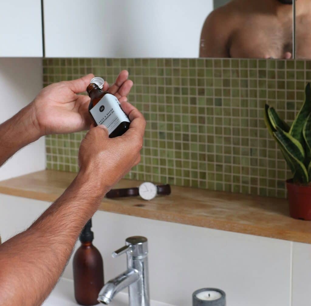 Man's hands opening a small bottle over a bathroom sink