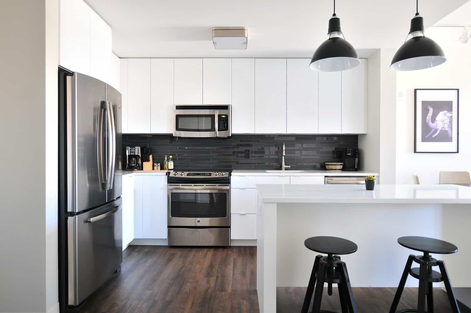 Modern white kitchen with stainless steel appliances and pendant lights