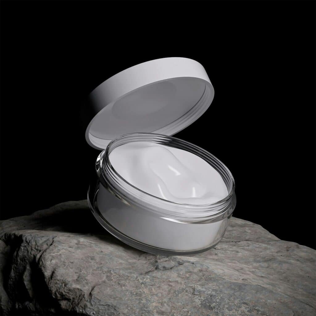 Open jar of white cream on a rock against a black background