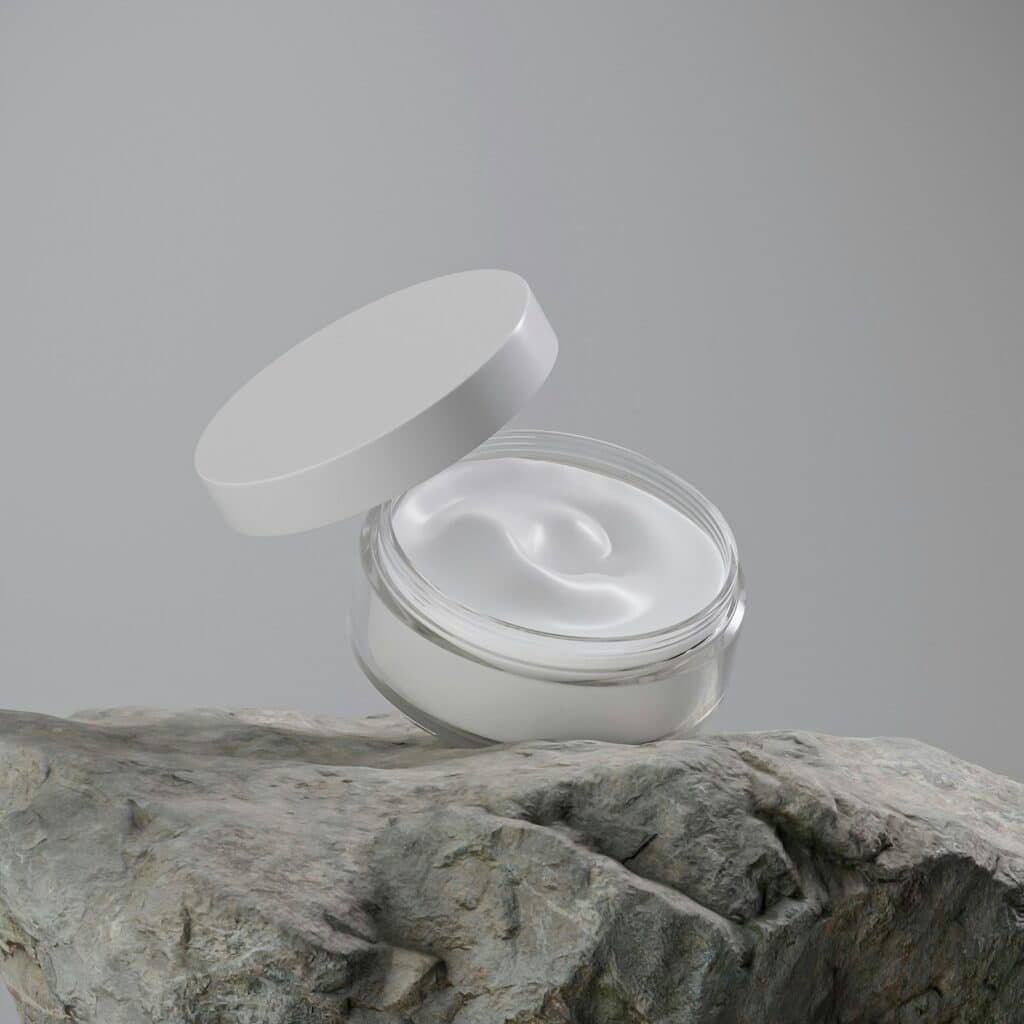 Open jar of white cream resting on a rock