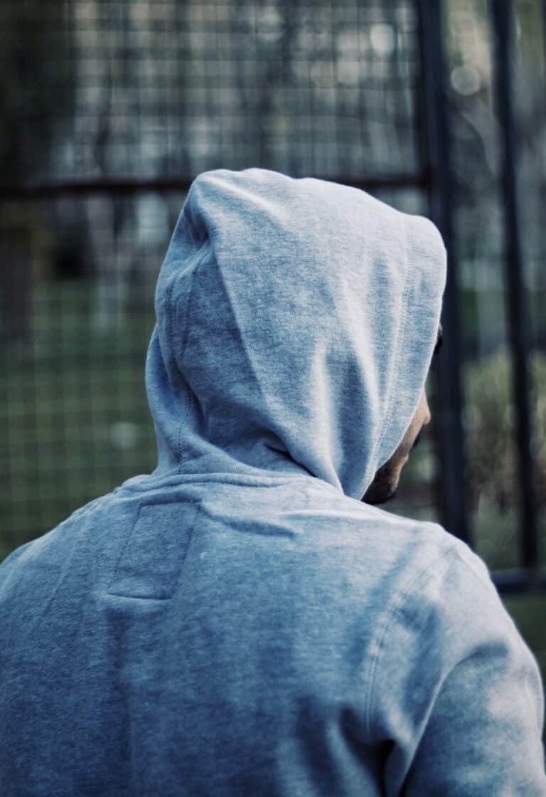 Person in a grey hoodie with the hood up, seen from behind
