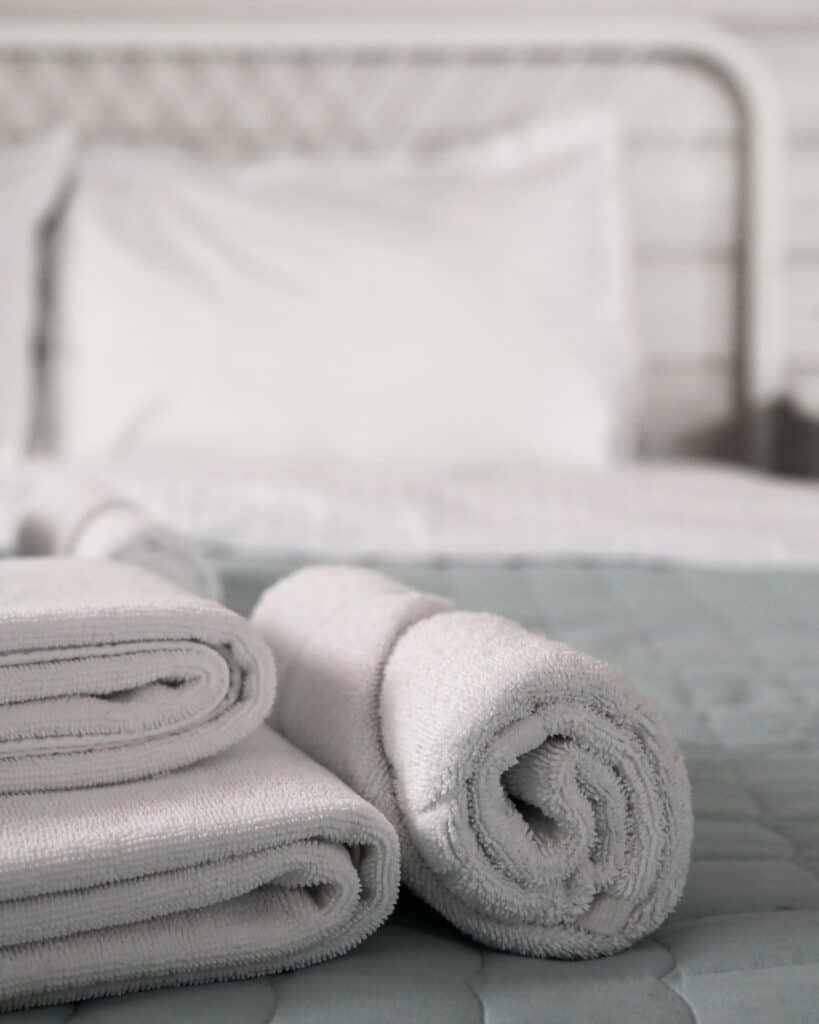 Rolled white towels on a bed