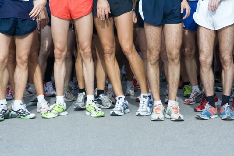 Runners in shorts and running shoes lined up at a start line