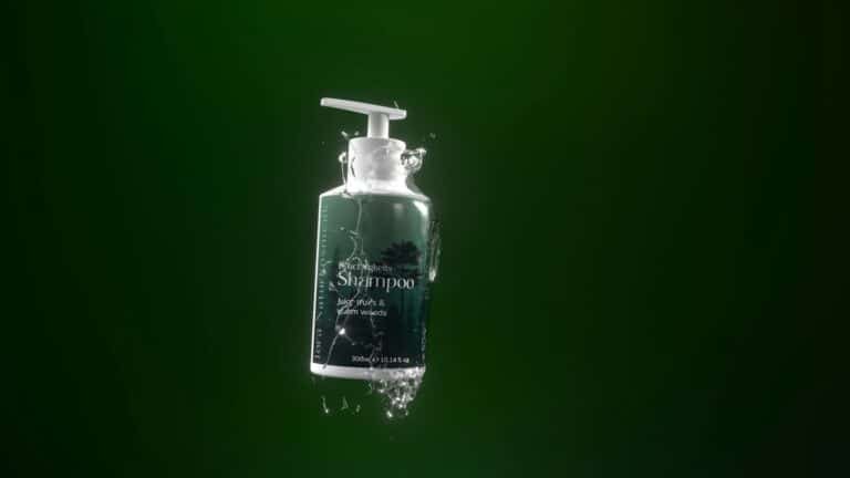 Shampoo bottle splashing in water against a dark green background
