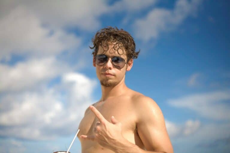 Shirtless man in sunglasses under a bright blue sky
