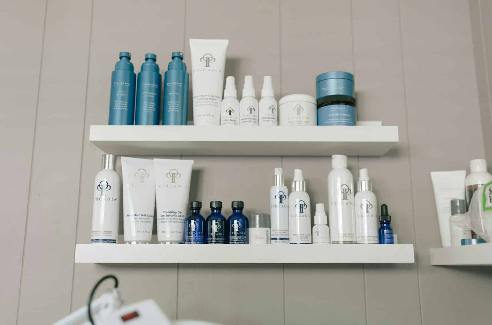 Skincare bottles and jars lined up on white shelves