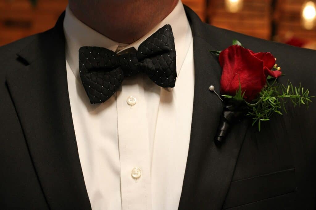 Tuxedo with a black bow tie and a red rose boutonniere