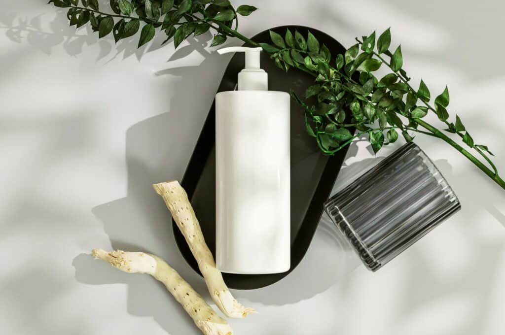 White pump bottle on a dark tray with greenery
